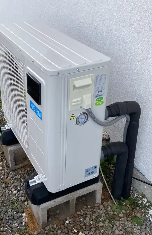 Venkovní jednotka tepelného čerpadla u fasády domu